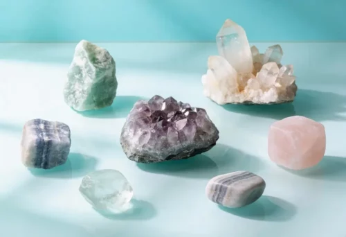 Un grupo de siete cristales y minerales surtidos se disponen sobre una superficie azul claro con fondo turquesa.