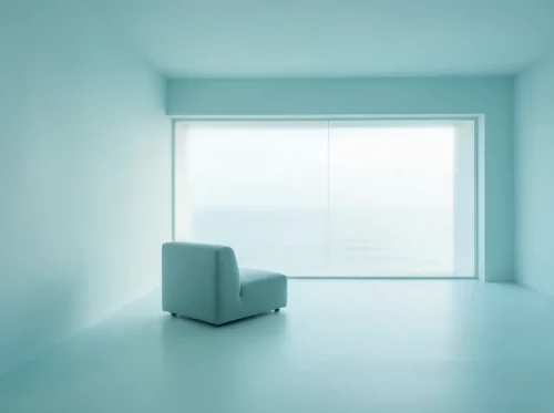 Un único sillón azul claro en una habitación minimalista con un gran ventanal esmerilado, suavemente iluminado por la luz natural, creando una atmósfera que irradia tranquilidad y energía a distancia.